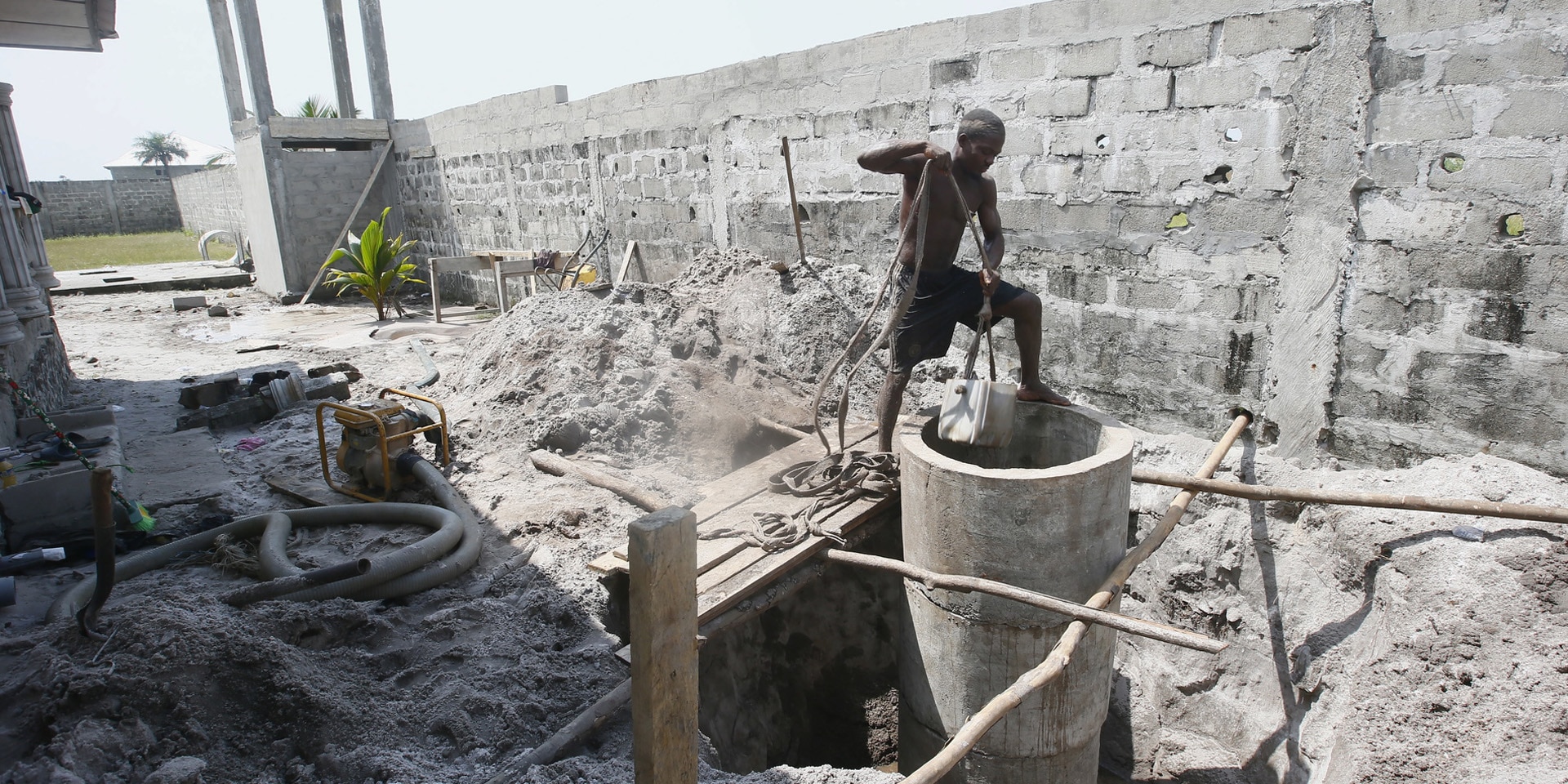 Un uomo spala in un cantiere per la costruzione di un pozzo.