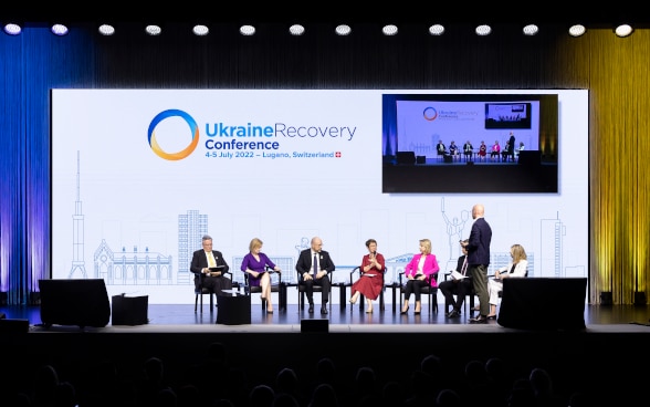 From left to right: Matthias Cormann (OECD), Elizabeth Truss (UK), Denys Shmyhal (UA), Odile Renaud-Basso (EBRD), Teresa Czerwinska (EIB), Valdis Dombrovskis  (European Commission) and Anna Bjerde (World Bank) speak during the plenary session of the conference.