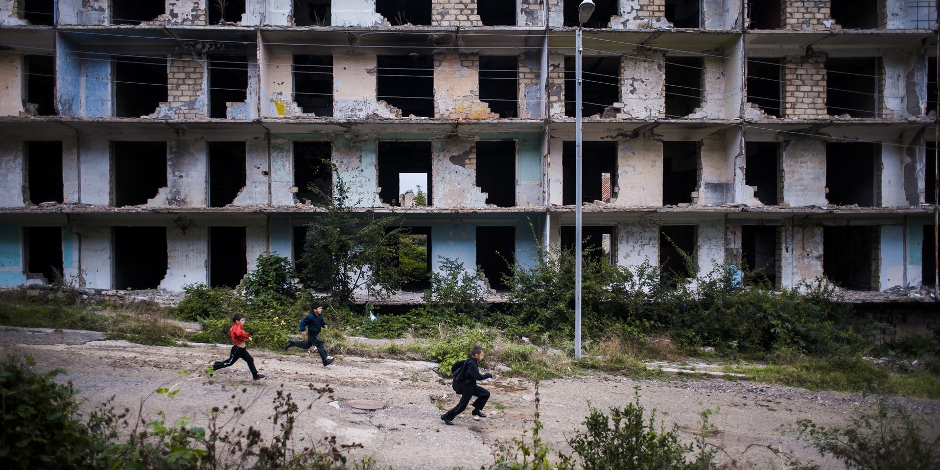 Nagorno-Karabakh: children walking past a war-damaged building.