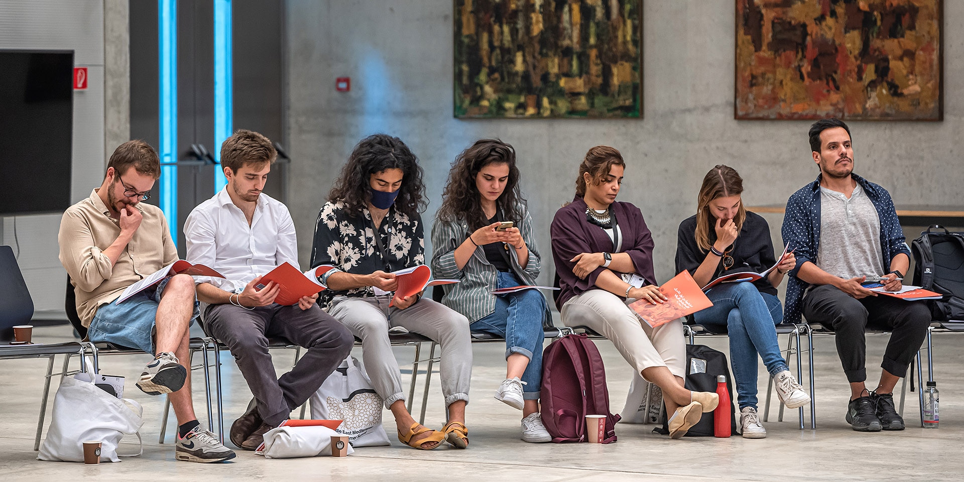 Seven young people are sitting on chairs. They are reading the FDFA's MENA strategy.