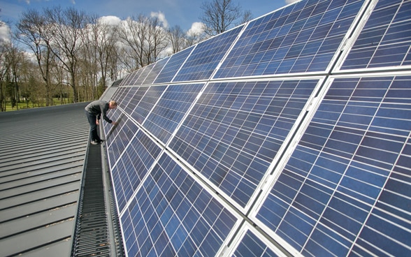 Un uomo lavora ad una struttura di pannelli solari.
