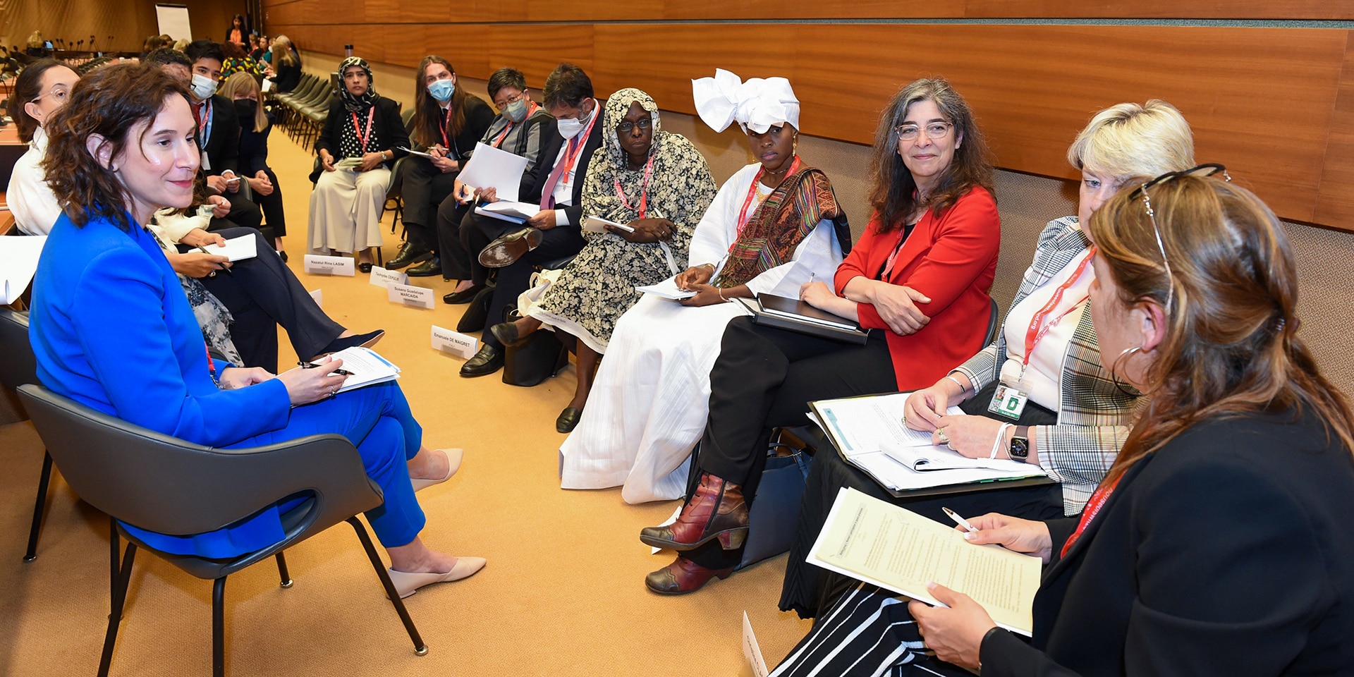 A group of participants at the Geneva meeting discuss in a circle.