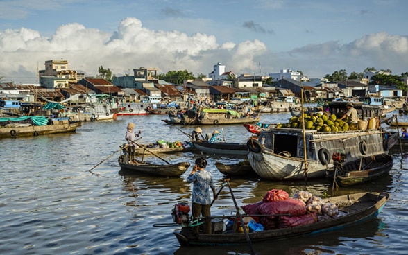 Frauen stehen am Steuer von Booten, die Lebensmittel auf dem Mekong-Fluss transportieren. 