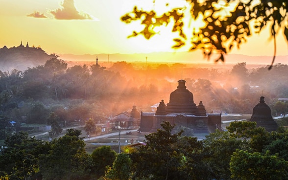 Un tempio e una casa nella nebbia nello Stato di Rakhine in Myanmar al tramonto. 