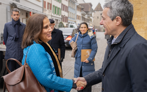 Il consigliere federale Cassis e la ministra degli esteri Urrejola Noguera si stringono la mano. Sullo sfondo si vedono le case di Murten.