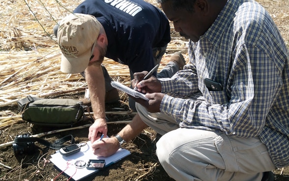 Deux personnes cartographient un champ de mines.