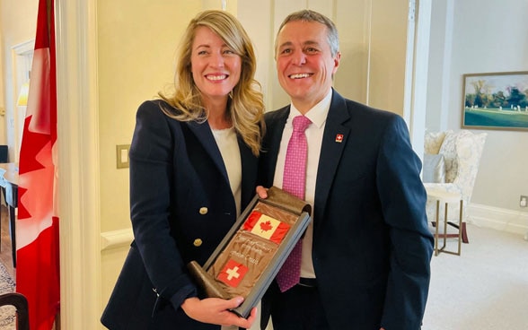 Federal Councillor Ignazio Cassis stands to the right of Foreign Minister Joly, who holds a plaque with the flags of Canada and Switzerland.