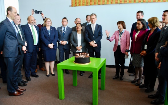 Vertrerinnen und Vertreter der ACT-Gruppe stehen rund um einen Kuchen.