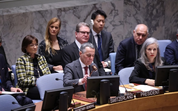 Le conseiller fédéral Ignazio Cassis est assis à la table en forme de fer à cheval du Conseil de sécurité de l'ONU et tape avec un marteau en bois.