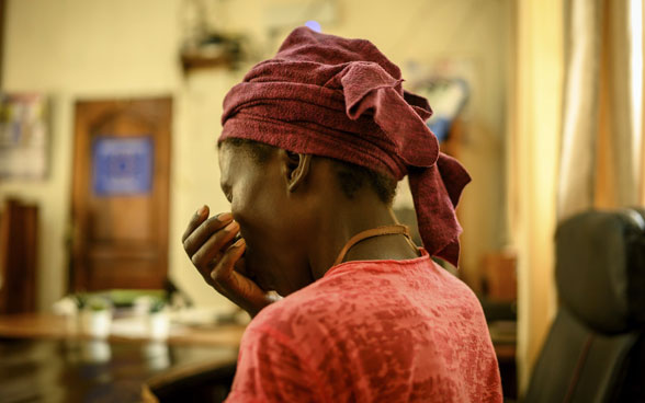 Une femme d’origine africaine est prise en photo de dos et met sa main devant sa bouche.