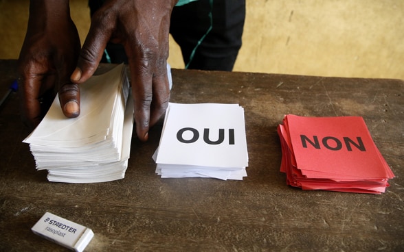  Des bulletins de vote sur lesquels sont écrits «Oui» et «Non» sont posés sur une table en bois.
