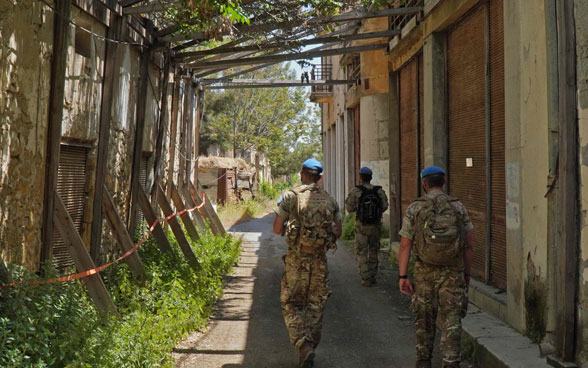 Des membres de la force de maintien de la paix de l’ONU, l’UNFICYP, traversent une ruelle entre des bâtiments en ruine dans la zone tampon.