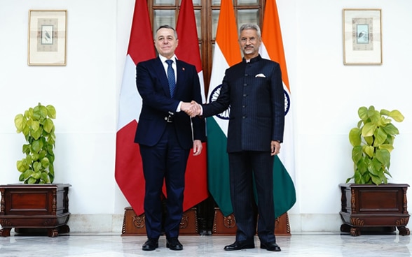 Ignazio Cassis et le ministre Subrahmanyam Jaishankar se serrent la main devant les drapeaux de leur pays respectif.