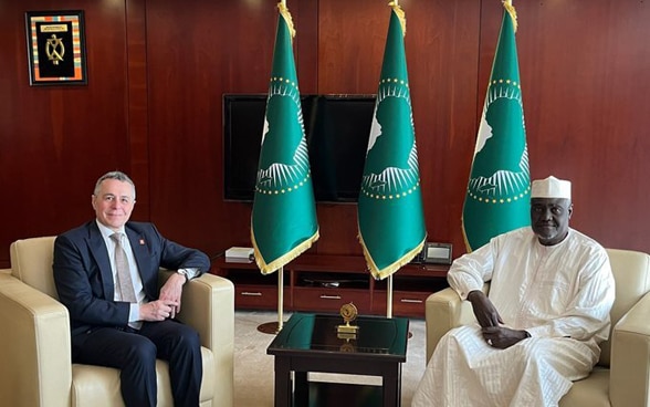 Ignazio Cassis and Moussa Faki Mahamat sit on white armchairs.