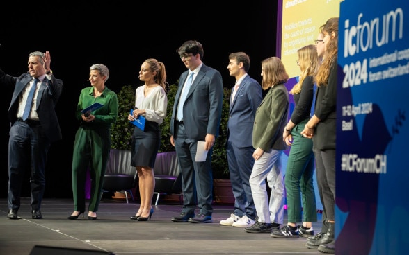 Ignazio Cassis e i giovani in piedi su un palco.