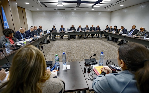 Women and men sit at tables and negotiate.
