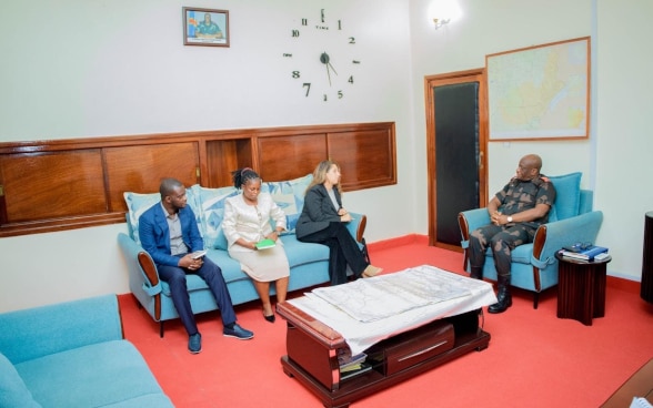 Laura Reymond-Joubin est assise sur un divan à trois place. Elle discute, sur sa gauche, au gouverneur militaire de la province de l’Ituri, installé sur un fauteuil.