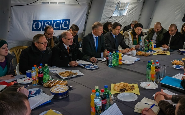 Réunis sous une tente, des représentants suisses de l’OSCE dirigent une rencontre organisée début 2016, près de la ligne de démarcation administrative à Ergneti, en Géorgie, entre les délégations russe, géorgienne et sud-ossète.