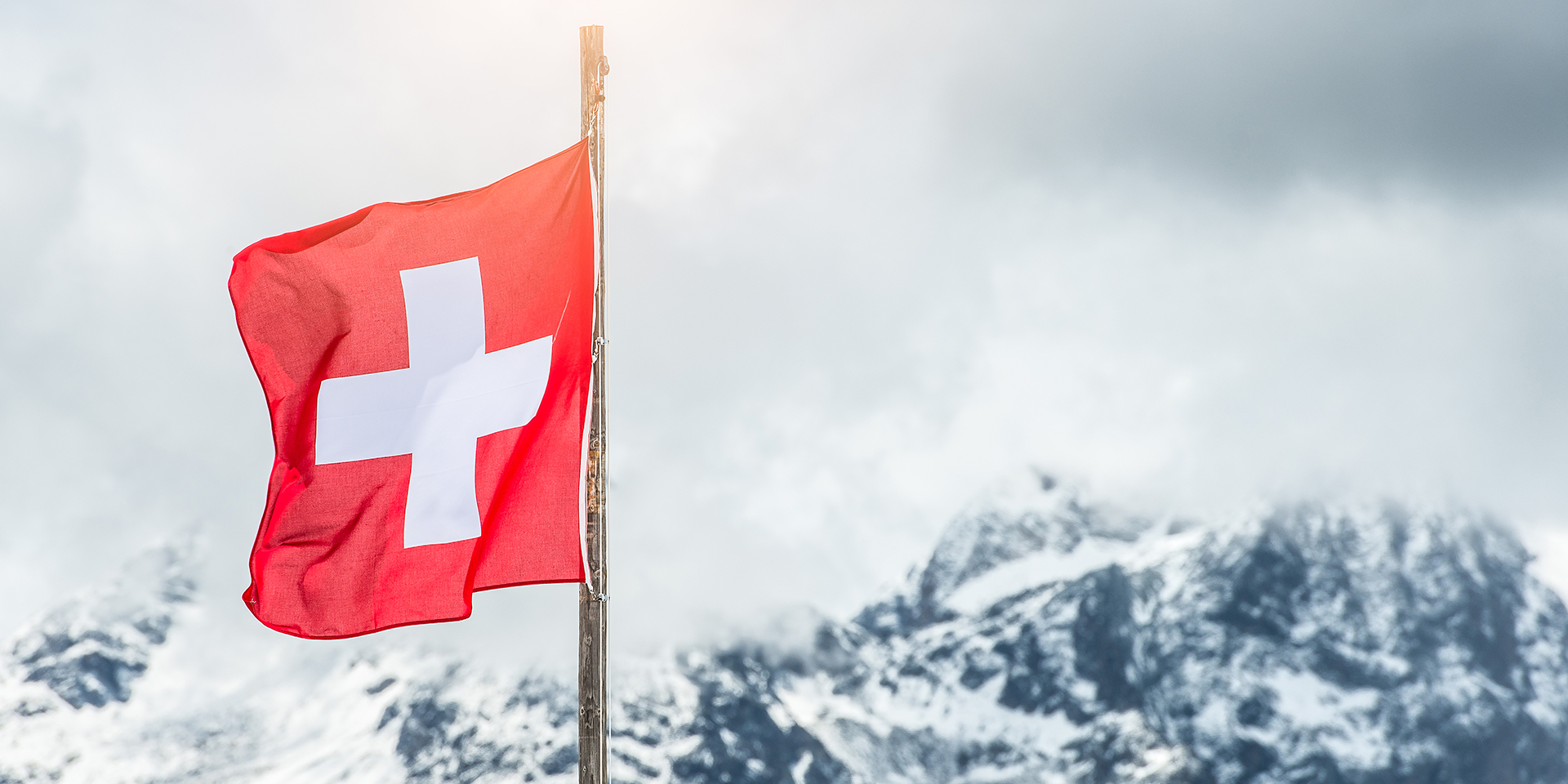 Drapeau suisse devant des montagnes.