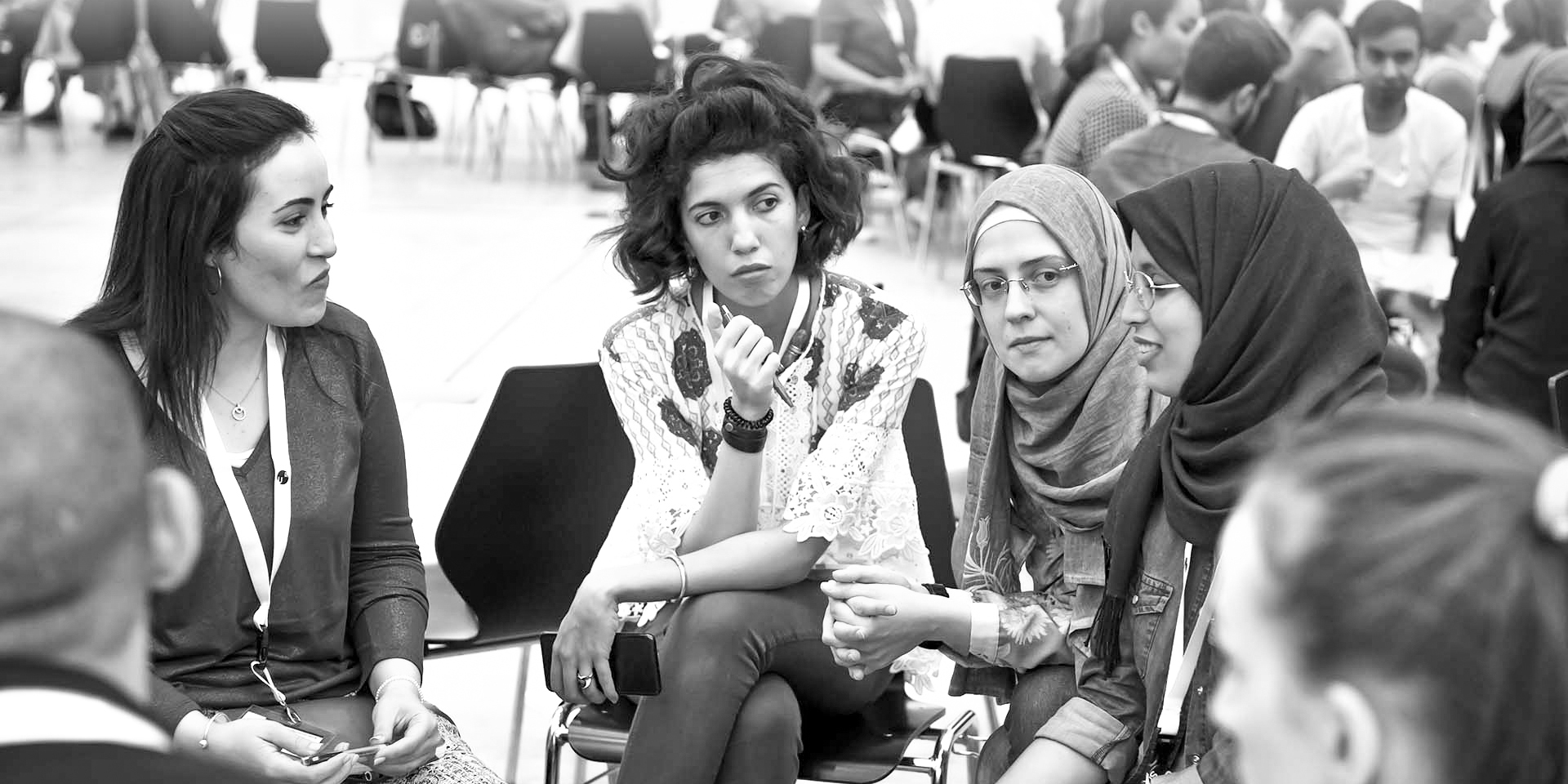  Four young girls are sitting in chairs, chatting together.