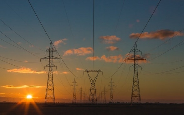 Viele Hochspannungsleitungen von der untergehenden Sonne beleuchtet