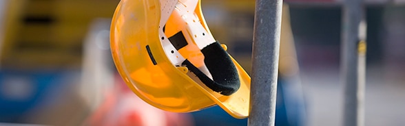 Casque de protection jaune suspendu à un échafaudage de chantier.