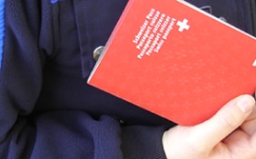 A border guard checks a Swiss passport and ID card