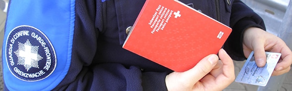 Une garde-frontière contrôle un passeport suisse et une carte d'identité