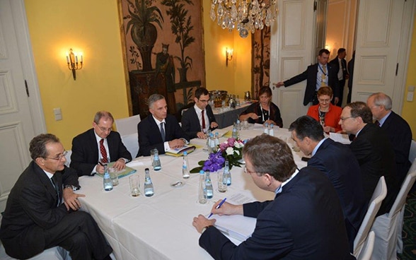 Membres des délégations assis à la table des négociations.