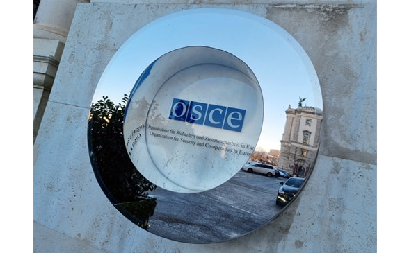 The OSCE's logo on a house wall behind glass.