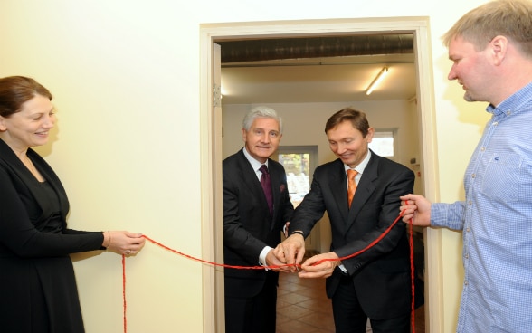 L’ambasciatore svizzero (a sinistra) taglia il nastro durante l’inaugurazione della nuova cucina, aiutato dal presidente del Consiglio direttivo del ALTUM.