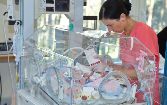 A nurse takes care of an infant in an incubator.