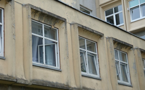 Three open windows in the top storey of a building. 