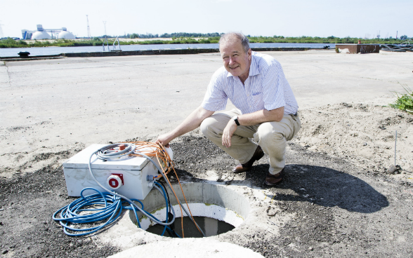 A man sitting in front of a remediation well at an industrial port
