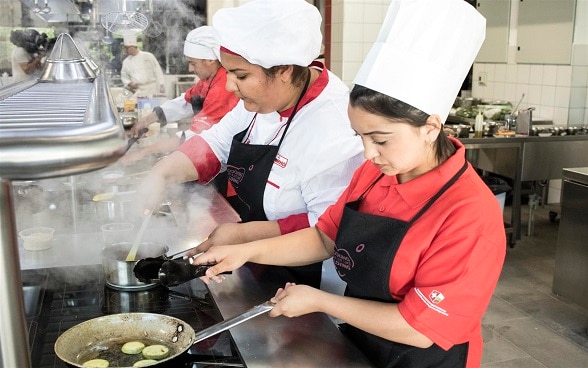 Women cooking in a large kitchen.