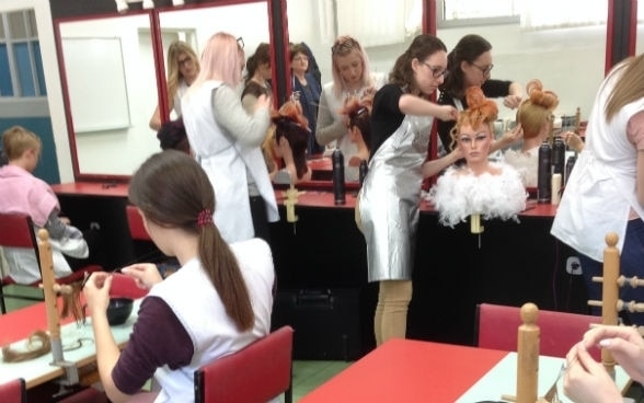 Young women practising on dummies in a hairdressing salon.
