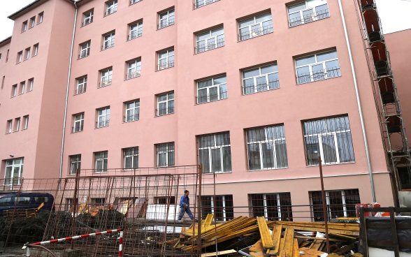 Construction worker in front of a building whose renovation is almost completed.