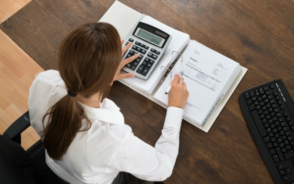 Femme d’affaires penchée sur une calculatrice et un classeur