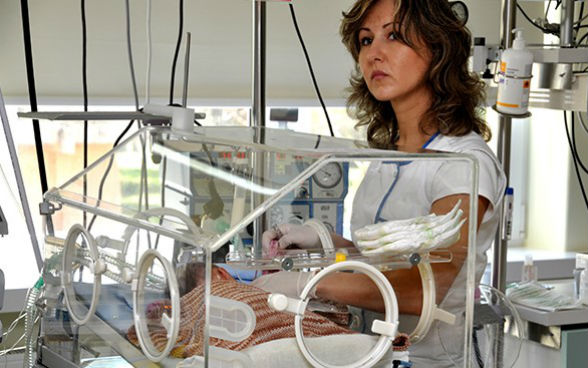 A nurse monitors the health of a premature baby in an incubator.