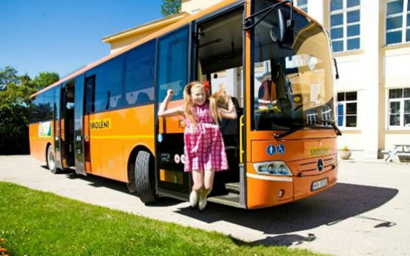 Una bambina salta davanti a uno scuolabus.