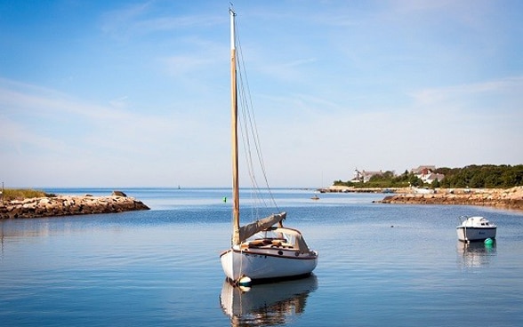 Ein kleines Segelschiff liegt an der Küste vor Anker.